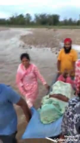 बेहट: फतेहपुर की नदी में सैलाब आने के चलते बीमार महिला को नदी से होकर स्ट्रेचर पर ले जाते दिखाई दिए परिजन