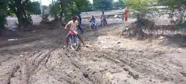 पलवल: बागपुर की सड़क बाढ़ से कट जाने के कारण लोग खेतों से बाइक निकालने हेतु हो रहे हैं मजबूर, करना पड़ रहा है परेशानी का सामना