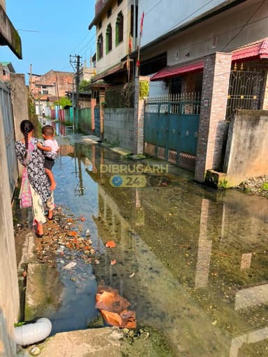 #Dibrugarh | Residents of Padumnagar 1 in Dibrugarh have expressed growing frustration over the poor condition of roads and the lack of a proper drainage system in the locality, alleging that the issue has remained unresolved for years despite repeated complaints to the authorities.
According to local residents, the road remains submerged in dirty drain and sewage water almost every day, irrespective of rainfall. The stagnant water not only causes inconvenience to commuters and pedestrians but also poses serious health and sanitation concerns for the people living in the area.
The situation reportedly worsens during the monsoon season, when even moderate rainfall leads to severe waterlogging, making it difficult for residents to move around and affecting daily activities. Locals claim that numerous complaints and applications have been submitted to the concerned departments over the years, but no permanent solution has been implemented.