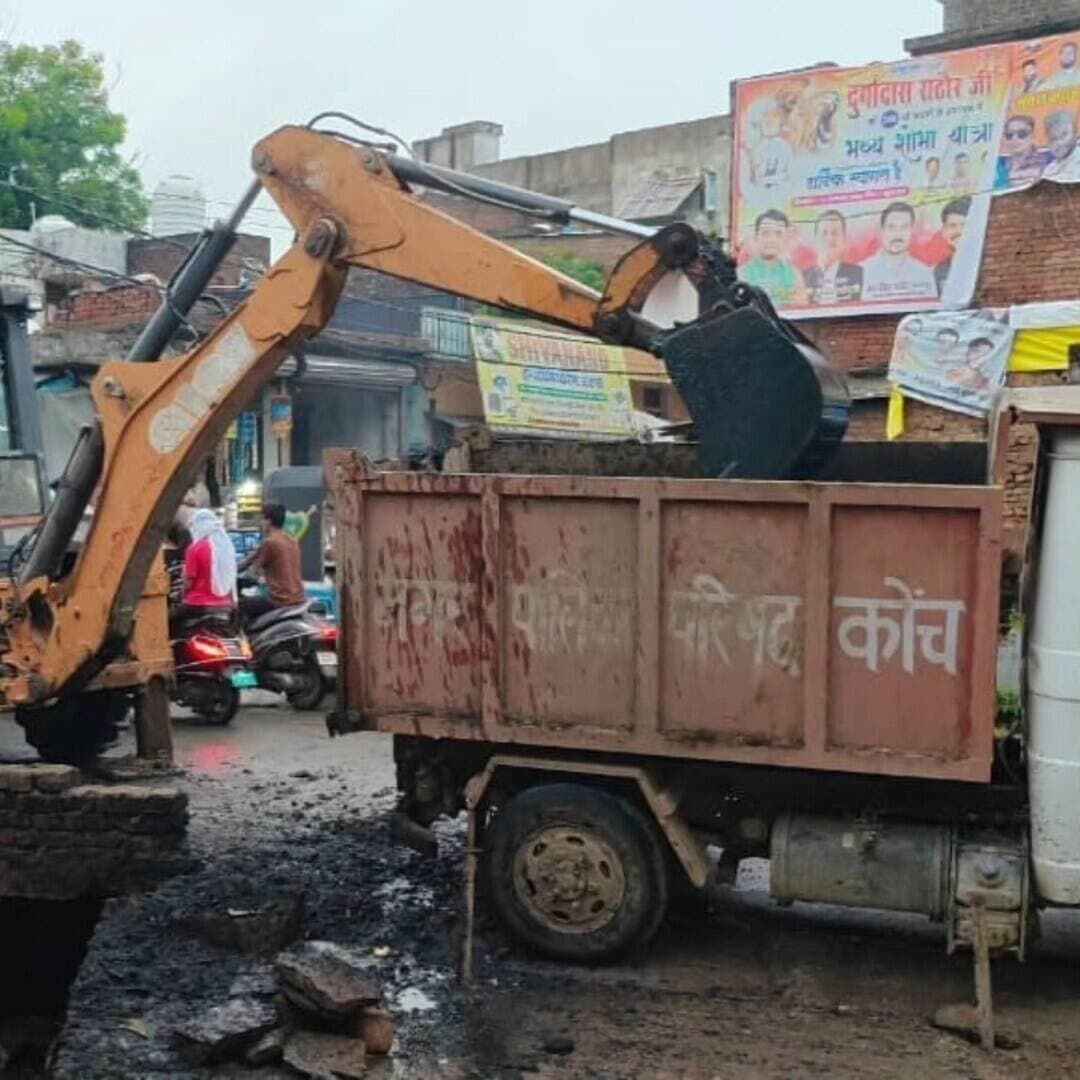 चंदकुआं पर नाला सफाई के लिए पहुंची जेसीबी फोटो खिंचा कर वापस लौटी
भूतेश्वर मंदिर में घुटनों तक नाले के पानी में खड़े होकर आरती करते पुजारी का वीडियो वायरल होने के बाद नींद खुली पालिका की
कोंच। 15 अगस्त को हुई बारिश ने नगर पालिका की नाला सफाई व्यवस्था की पोल खोल दी। बारिश के बाद कस्बे की कई सड़कें तालाब में तब्दील हो गईं और चंदकुआं चौराहे पर जलभराव के चलते लोगों के घरों, दुकानों से लेकर मंदिर और अस्पताल तक पानी पहुंच गया। प्राचीन भूतेश्वर मंदिर भी जलभराव की चपेट में आ गया और दूषित पानी शिवलिंग तक पहुंच गया।
जलभराव के बीच मंदिर में पुजारी द्वारा आरती किए जाने का वीडियो सोशल मीडिया पर वायरल होने के बाद नगर पालिका की कार्यशैली पर सवाल उठने लगे। प्रशासन के उच्चाधिकारियों ने मामले का संज्ञान लेते हुए नगर पालिका प्रशासन को तत्काल नालों की सफाई कराने के निर्देश दिए।वीडियो वायरल होने के अगले ही दिन पालिका की टीम चंदकुआं पहुंची और जेसीबी की मदद से नाले की सफाई शुरू कराई। बताया गया कि नाले की एक जगह से ही कई ट्रॉली मलबा निकला। इसके बावजूद कुछ देर की कार्रवाई के बाद अभियान बंद कर दिया गया। स्थानीय लोगों का आरोप है कि नाला सफाई के नाम पर महज खानापूर्ति की गई। उनका कहना है कि पालिका की टीम कुछ देर तक जेसीबी चलाने के बाद फोटो खिंचवाकर मौके से चली गई। यदि नाले की पूरी तरह सफाई कराई जाती तो जलनिकासी की समस्या का समाधान हो सकता था। लोगों का कहना है कि नालों की नियमित सफाई और जलनिकासी की समुचित व्यवस्था नहीं होने के कारण हर वर्ष उन्हें जलभराव की समस्या से जूझना पड़ता है। अब देखना यह है कि पालिका प्रशासन फोटो सेशन तक सीमित इस कार्रवाई को आगे बढ़ाकर जलनिकासी की समस्या का स्थायी समाधान कराता है या फिर अगली बारिश का इंतजार करता है।
नालों पर अतिक्रमण हटवाने के लिए कराया जा रहा ऐलान
कोंच। जलभराव की समस्या को देखते हुए एसडीएम अभिनव कुमार यादव ने बताया कि नगर पालिका प्रशासन द्वारा नालों पर किए गए अतिक्रमण को हटवाने के लिए ऐलान कराया जा रहा है। उन्होंने कहा कि नालों पर अतिक्रमण के कारण सही से नाला सफाई नहीं हो पा रही है। अतिक्रमण हटने के बाद नालों की सफाई कराकर जलनिकासी व्यवस्था को बेहतर कराया जाएगा।