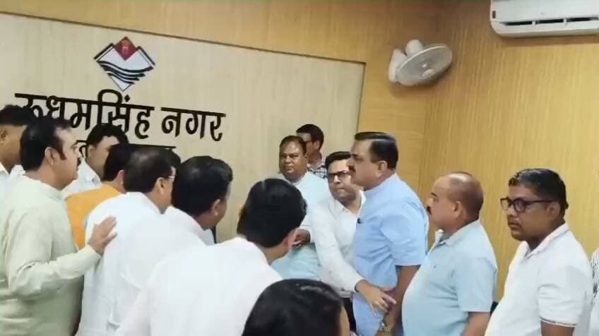कमिश्नर के सामने भिड़े विधायक और पूर्व विधायक
एंकर- रुद्रपुर में SIR बैठक के दौरान भाजपा और कांग्रेस नेताओं के बीच तीखी नोकझोंक के बाद कलेक्ट्रेट परिसर में तनाव की स्थिति बन गई। भाजपा नेताओं ने आपत्तिकर्ताओं को धमकाने के आरोप लगाते हुए धरना शुरू कर दिया। मौके पर भारी पुलिस बल तैनात किया गया है।रुद्रपुर में कुमाऊं कमिश्नर दीपक रावत की अध्यक्षता में SIR यानी विशेष गहन पुनरीक्षण को लेकर बैठक आयोजित की गई थी। बैठक में मतदाता सूची में कथित डबल वोट और अन्य आपत्तियों को लेकर भाजपा और कांग्रेस नेताओं के बीच तीखी बहस हो गई। भाजपा के पूर्व विधायक राजेश शुक्ला ने आरोप लगाया कि SIR के दौरान आपत्ति दर्ज कराने वाले लोगों को फोन और घर जाकर धमकाया जा रहा है। उन्होंने प्रशासन से मामले की जांच और दोषियों के खिलाफ कार्रवाई की मांग की।विवाद बढ़ने के बाद भाजपा जिला अध्यक्ष कमल जिंदल, पूर्व विधायक राजेश शुक्ला, रुद्रपुर विधायक शिव अरोड़ा समेत अन्य भाजपा पदाधिकारी कलेक्ट्रेट कक्ष के बाहर धरने पर बैठ गए। बड़ी संख्या में भाजपा और कांग्रेस समर्थक भी कलेक्ट्रेट परिसर में पहुंच गए। स्थिति को देखते हुए भारी पुलिस बल तैनात किया गया है। भाजपा नेताओं का कहना है कि उनकी मांग निष्पक्ष और शुद्ध मतदाता सूची सुनिश्चित कराने की है।