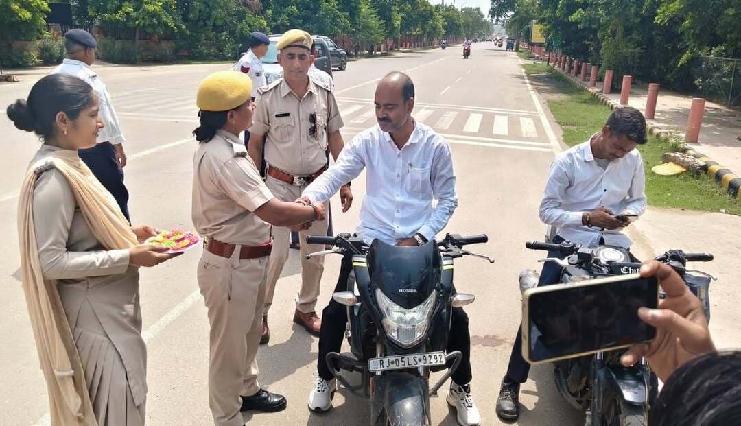 #भरतपुर। जिला पुलिस अधीक्षक राजेश कुमार मीना के निर्देशन में यातायात पुलिस और कालिका पेट्रोलिंग यूनिट की महिला पुलिसकर्मियों ने रक्षाबंधन के अवसर पर एक प्रेरणादायक पहल की। यातायात चौराहा पर बिना हेलमेट या तीन सवारी बैठाकर चल रहे दोपहिया वाहन चालकों को रोककर महिला पुलिसकर्मियों ने उनकी कलाई पर स्नेह की डोर रक्षासूत्र बांधी। इसके साथ ही उनसे चालान से बचने के लिए नहीं, बल्कि स्वयं और दूसरों के जीवन की सुरक्षा के लिए यातायात नियमों का पालन करने का वचन लिया। इस भावुक समझाइश से अभिभूत होकर वाहन चालकों ने अपनी भूल स्वीकार की और सहर्ष सुरक्षा नियमों को निभाने का वादा किया। यातायात पुलिस ने आमजन से भी अपील की है कि वे दोपहिया वाहन चलाते समय अनिवार्य रूप से हेलमेट पहनें और नियमों का पालन कर अपने परिवार की सुरक्षा सुनिश्चित करें।
