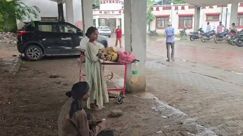 पत्नी की मौत के बाद शव ले जाने तक के पैसे नहीं, झांसी मेडिकल कॉलेज की तस्वीर ने झकझोरा
मां के शव के पास घंटों रोती रही मासूम बेटी, पुलिसकर्मी की संवेदनशील पहल बनी सहारा
मानवीयता की मिसाल: झांसी पुलिस ने एंबुलेंस की व्यवस्था कर शव को मध्य प्रदेश स्थित घर भिजवाया
झांसी। उत्तर प्रदेश के झांसी मेडिकल कॉलेज से सामने आई एक मार्मिक घटना ने हर संवेदनशील व्यक्ति को भावुक कर दिया। 36 वर्षीय महिला की मृत्यु के बाद उसके परिजनों के पास शव को गृह जनपद ले जाने तक के लिए पर्याप्त पैसे नहीं थे। मेडिकल कॉलेज की इमरजेंसी के बाहर पति अपनी पत्नी के शव के पास घंटों बेबस बैठा रहा, जबकि करीब आठ वर्ष की मासूम बेटी अपनी मां के शव के पास बिलखती रही। यह दृश्य वहां मौजूद लोगों की आंखें नम कर गया।
जानकारी के अनुसार, 4 सितंबर 2026 को थाना नवाबाद क्षेत्र के मेडिकल कॉलेज परिसर में उपचार के दौरान एक 36 वर्षीय महिला की मृत्यु हो गई। महिला का परिवार आर्थिक रूप से बेहद कमजोर था और शव को अपने गृह जनपद ओरछा, जिला निवाड़ी (मध्य प्रदेश) ले जाने के लिए उनके पास पर्याप्त धनराशि उपलब्ध नहीं थी। मजबूरी में परिजन मेडिकल कॉलेज परिसर में ही शव के साथ बैठे रहे।
इसी दौरान मेडिकल चौकी पर तैनात पुलिसकर्मियों की नजर इस परिवार पर पड़ी। मामले की जानकारी मिलते ही प्रभारी मेडिकल चौकी ने मानवीय संवेदनशीलता का परिचय देते हुए तत्काल पहल की। पुलिस ने परिजनों से समन्वय स्थापित किया और एंबुलेंस की व्यवस्था कर महिला के शव को सम्मानपूर्वक उसके गृह जनपद ओरछा भिजवाया।
यह घटना केवल एक परिवार की आर्थिक बेबसी की कहानी नहीं, बल्कि यह भी दर्शाती है कि कठिन परिस्थितियों में प्रशासन और पुलिस की संवेदनशील पहल किसी पीड़ित परिवार के लिए बड़ी राहत बन सकती है। झांसी पुलिस की इस मानवीय कार्रवाई की स्थानीय लोगों और सोशल मीडिया पर भी सराहना की जा रही है।
हालांकि यह घटना स्वास्थ्य व्यवस्था और आर्थिक रूप से कमजोर परिवारों के सामने आने वाली चुनौतियों को भी उजागर करती है। विशेषज्ञों का मानना है कि जरूरतमंद परिवारों को ऐसी परिस्थितियों में तत्काल सहायता उपलब्ध कराने के लिए अस्पतालों और प्रशासन के बीच बेहतर समन्वय आवश्यक है।
🟥 ND NEWS | दैनिक निष्पक्ष धारा की अपील
किसी भी अस्पताल में यदि कोई जरूरतमंद परिवार आर्थिक संकट में दिखाई दे तो समाज, स्वयंसेवी संस्थाएं और प्रशासन मिलकर उनकी सहायता के लिए आगे आएं। पुलिस द्वारा दिखाई गई संवेदनशीलता समाज के लिए प्रेरणादायक है। मानवता और करुणा ही किसी भी सभ्य समाज की सबसे बड़ी पहचान है।
जनहित सुझाव:
अस्पतालों में असहाय परिवारों के लिए आपातकालीन सहायता तंत्र को और मजबूत किया जाए।
जरूरतमंद मरीजों और परिजनों को सरकारी सहायता योजनाओं की तत्काल जानकारी उपलब्ध कराई जाए।
सामाजिक संगठन और नागरिक ऐसे परिवारों की मदद के लिए आगे आएं।
पुलिस और स्वास्थ्य विभाग की मानवीय पहल को प्रोत्साहित किया जाए।
👇👇
#NDNEWS #दैनिकनिष्पक्षधारा #Jhansi #JhansiMedicalCollege #JhansiPolice #Humanity #MedicalCollege #UPPolice #HelpingHands #Compassion #BreakingNews #UttarPradesh
👇👇👇
@dgpup
@RSSorg
@UPGovt
@RSSgeet
@wpl1090
@Uppolice
@MIB_India
@PMOIndia
@HMOIndia
@VHPDigital
@InfoDeptUP
@myogioffice
@homeupgov
@CMOUP_RC
@CMOfficeUP
@ChiefSecyUP
@ChiefSecyUP
@MahantYogiG
@UpPolicemitra
@BajrangDalOrg
@UPPViralCheck
@rashtrapatibhvn
@112UttarPradesh
@UPMahilakalyan
@myogiadityanath
@JhansiPolice
@Uppolice
@dgpup
@UPGovt
@CMOfficeUP
@myogiadityanath
@InfoDeptUP
@nhm_up
👇👇
🟥 ND NEWS | दैनिक निष्पक्ष धारा
मुख्य संपादक / संस्थापक: राजन सिंह हाड़ा
सह-संपादक: शालिनी सिंह भदौरिया
✒️ रिपोर्ट: यूपी हेड नागेंद्र पांडये
📍 कार्यालय-3: U158, हीरा स्वीट्स के पास, विकास मार्ग, लक्ष्मी नगर, पूर्वी दिल्ली, पिन कोड – 110092 (NCR)
📍 कार्यालय-2: विधानसभा रोड, बर्लिंगटन चौराहा, लखनऊ – 226001 (UP)
📍 कार्यालय-1: 1/1 अटल बिहारी चौराहा, नियर बर्मा चौराहा, फतेहपुर – 212601 (UP)
📅 दिनांक: 05 सितंबर 2026
📆 दिन: शनिवार
📧 Email: ndnewschannel@gmail.com
📞 मोबाइल: 096961 19696