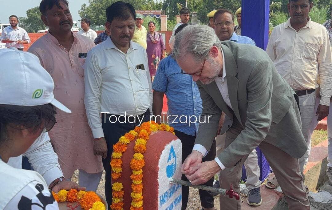 डेनमार्क के राजदूत ने मिर्जापुर में ग्रामीण जलापूर्ति योजना समुदाय को सौंपी
दुहौआ गांव में ‘जल अर्पण’ समारोह, जल संरक्षण और सामुदायिक स्वामित्व पर दिया जोर
मिर्जापुर, 15 सितंबर 2026। भारत में डेनमार्क के राजदूत महामहिम रासमुस अबिल्डगार्ड क्रिस्टेंसन ने मंगलवार को मिर्जापुर के दुहौआ गांव पहुंचकर ‘जल अर्पण’ समारोह में भाग लिया। जल जीवन मिशन के अंतर्गत संचालित ग्रामीण जलापूर्ति योजना को औपचारिक रूप से स्थानीय समुदाय को सौंपा गया।
कार्यक्रम में जिलाधिकारी पवन कुमार गंगवार, मुख्य विकास अधिकारी विशाल कुमार, अपर जिलाधिकारी नमामि गंगे विजेता, अपर जिलाधिकारी विनोद सिंह, यूएनओपीएस इंडिया के कंट्री मैनेजर सहित 400 से अधिक ग्रामीणों, विशेष रूप से महिलाओं ने सहभागिता की।
राजदूत ने सबसे पहले लालगंज के नरैना कला गांव स्थित वाटर ट्रीटमेंट प्लांट का निरीक्षण किया। उन्होंने जल शोधन की प्रक्रिया, एससीएडीए प्रणाली तथा बेलन नदी से जल लेकर उसे उपचारित कर घरों तक पहुंचाने की व्यवस्था की जानकारी ली। यह बहु-ग्रामीय योजना 258 गांवों में स्वच्छ पेयजल की आपूर्ति कर रही है।
इसके बाद प्रतिनिधिमंडल दुहौआ गांव पहुंचा, जहां प्रशिक्षित जल सखियों ने पारंपरिक तरीके से राजदूत का स्वागत किया। ग्रामीण जलापूर्ति योजना के संचालन का जायजा लेने के साथ ग्रामीणों से संवाद किया गया। परसिया स्थित ओवरहेड टैंक पर राजदूत ने पंप संचालक से बातचीत की और ‘जल बंधन’ गतिविधि में हिस्सा लिया। उन्होंने परिसर में पौधारोपण भी किया।
जल संरक्षण की दिलाई सामूहिक शपथ
जय प्रकाश नारायण सर्वोदय बालक विद्यालय, परसिया में आयोजित ‘जल अर्पण’ समारोह में दीप प्रज्वलन के बाद जल गुणवत्ता परीक्षण का लाइव प्रदर्शन किया गया। बच्चों ने ‘जल बिना भविष्य’ विषय पर लघु नाटिका प्रस्तुत कर जल संरक्षण का संदेश दिया।
कार्यक्रम में ‘जल वंदना’ और ‘जल श्रृंगार’ के माध्यम से जलापूर्ति योजना को समुदाय को सौंपने की प्रक्रिया पूरी की गई। अंत में ग्रामीणों और बच्चों को जल संरक्षण एवं जिम्मेदारीपूर्वक जल उपयोग की सामूहिक शपथ दिलाई गई।
डेनमार्क के राजदूत रासमुस अबिल्डगार्ड क्रिस्टेंसन ने कहा कि भारत और डेनमार्क के बीच जल क्षेत्र में लंबे समय से मजबूत साझेदारी है। उन्होंने कहा कि जल संसाधनों के सतत और कुशल प्रबंधन के साथ उन समुदायों की सक्रिय भागीदारी जरूरी है, जो इन संसाधनों पर निर्भर हैं।
यूएनओपीएस इंडिया के कंट्री मैनेजर विनोद मिश्रा ने जल की उपलब्धता, पहुंच और गुणवत्ता को जल सुरक्षा के तीन प्रमुख आयाम बताते हुए समुदाय स्तर पर जल गुणवत्ता की निगरानी पर जोर दिया।
ग्राम जल एवं स्वच्छता समिति की सदस्य अमृता ने योजना के संचालन और प्रबंधन में समुदाय की भूमिका की जानकारी दी। कार्यक्रम में महिलाओं और स्थानीय संस्थाओं की भूमिका को ग्रामीण जल सेवाओं की निरंतरता के लिए महत्वपूर्ण बताया गया।
अपर जिलाधिकारी नमामि गंगे ने मिर्जापुर की दुर्गम भौगोलिक परिस्थितियों के बावजूद जलापूर्ति व्यवस्था में सुधार के लिए यूएनओपीएस की टीम के प्रयासों की सराहना की।
भारत-डेनमार्क ग्रीन स्ट्रेटेजिक पार्टनरशिप के तहत यूएनओपीएस उत्तर प्रदेश सहित चार राज्यों के 478 गांवों में जल जीवन मिशन को सहयोग प्रदान कर रहा है। उत्तर प्रदेश में वर्ष 2021 से शुरू हुई यह पहल 2026 तक 11 जिलों के 200 से अधिक गांवों तक पहुंच चुकी है।
#मिर्जापुर #Mirzapur #TodayMirzapurNews #डेनमार्क #DanishAmbassador #RasmusAbildgaardKristensen #जलजीवनमिशन #JalJeevanMission #जलअर्पण #ग्रामीणजलापूर्ति #जलसंरक्षण #जलसुरक्षा #UNOPS #उत्तरप्रदेश #मिर्जापुरन्यूज