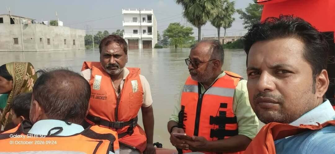 घर डूबे, रास्ते डूबे… हौसले नहीं डूबे: स्वास्थ्य टीम ने बाढ़ में बचाई कई जिंदगियां
• जलमग्न घरों से गर्भवती महिलाओं और बुजुर्गों का रेस्क्यू
• तीन महिलाओं का कराया सुरक्षित प्रसव
• जब चारों तरफ था पानी, तब स्वास्थ्यकर्मी बने सहारा
छपरा। चारों तरफ पानी ही पानी। घरों के दरवाजे तक पहुंच चुका सैलाब और बाहर निकलने का कोई रास्ता नहीं। कहीं गर्भवती महिला प्रसव पीड़ा से जूझ रही थी तो कहीं पांच फीट पानी से घिरे घर में अकेली वृद्ध महिला जिंदगी और मौत के बीच फंसी थी। ऐसे वक्त में जब बाढ़ग्रस्त गांवों में सामान्य आवाजाही तक मुश्किल हो गई थी, मकेर की स्वास्थ्य टीम लोगों के लिए उम्मीद की किरण बनकर सामने आई। 30 सितंबर से आई भीषण बाढ़ ने मकेर प्रखंड के कई इलाकों में जनजीवन को पूरी तरह प्रभावित कर दिया। कई गांवों का सड़क संपर्क टूट गया और बड़ी संख्या में लोग घरों में ही फंस गए। सबसे बड़ी चिंता उन गर्भवती महिलाओं और बुजुर्गों को लेकर थी, जिन्हें आपात स्थिति में तत्काल चिकित्सा सहायता की जरूरत थी। इस चुनौती के बीच प्राथमिक स्वास्थ्य केंद्र (PHC) मकेर के प्रभारी चिकित्सा पदाधिकारी डॉ. गोपाल कृष्ण की टीम ने प्रखंड मूल्यांकन एवं अनुश्रवण सहायक-सह-प्रखंड स्वास्थ्य प्रबंधक अमित कुमार सिंह के नेतृत्व में राहत और स्वास्थ्य सेवाओं का मोर्चा संभाला।
जलमग्न घर से गर्भवती महिला को निकाला, कराया सुरक्षित प्रसव
बाढ़ के बीच सबसे चुनौतीपूर्ण रेस्क्यू अभियानों में से एक बिक्रम कैतुका गांव में हुआ। गांव की जागृति कुमारी, पति धुरंधर बैठा, बाढ़ के पानी के बीच अपने घर में फंस गई थीं। उनकी स्थिति को देखते हुए तत्काल मदद की जरूरत थी। घर तक पहुंचने के रास्ते पूरी तरह जलमग्न थे। सूचना मिलते ही स्वास्थ्य विभाग की टीम सक्रिय हुई। प्रखंड स्वास्थ्य प्रबंधक अमित कुमार सिंह ने एनडीआरएफ टीम के साथ समन्वय किया और खुद रेस्क्यू अभियान में शामिल हुए। एनडीआरएफ की मदद से जागृति कुमारी को जलमग्न घर से सुरक्षित बाहर निकाला गया। इसके बाद उन्हें आवश्यक स्वास्थ्य सुविधा उपलब्ध कराई गई और सुरक्षित प्रसव कराया गया। इस पूरे अभियान में समय पर सूचना, त्वरित समन्वय और स्वास्थ्य टीम की तत्परता ने जच्चा-बच्चा दोनों की सुरक्षा में अहम भूमिका निभाई।
फुलवरिया में भी बाढ़ के बीच पहुंची मदद
बाढ़ से घिरे फुलवरिया गांव में भी स्वास्थ्य विभाग के सामने ऐसी ही चुनौती थी। गांव की प्रीति कुमारी, पति तूफान राय, को प्रसव के लिए सुरक्षित स्वास्थ्य केंद्र तक पहुंचाना आसान नहीं था। चारों तरफ पानी और बाधित रास्तों के बावजूद स्वास्थ्य टीम ने उपलब्ध संसाधनों के सहारे उन्हें सुरक्षित तरीके से सीएचसी गरखा पहुंचाया, जहां उनका सफल प्रसव कराया गया। इसी गांव की तजमुन खातून, पति मो. मुस्लिम अली, भी बाढ़ के कारण सामान्य आवागमन से कट गई थीं। स्वास्थ्य टीम ने उनके परिवार से लगातार संपर्क बनाए रखा और प्रसव की स्थिति पर नजर रखी। जरूरी प्रबंध के बाद 1 अक्टूबर 2026 को उनका भी सुरक्षित प्रसव कराया गया।
बाढ़ के दौरान इन मामलों में स्वास्थ्य विभाग के सामने केवल अस्पताल तक मरीज पहुंचाने की चुनौती नहीं थी, बल्कि जलमग्न इलाकों में सुरक्षित तरीके से पहुंचना, परिवहन की व्यवस्था करना और समय पर चिकित्सा सुविधा उपलब्ध कराना भी बड़ी चुनौती थी।
पांच फीट पानी से घिरे घर में फंसी वृद्ध महिला का रेस्क्यू
गर्भवती महिलाओं तक स्वास्थ्य सुविधा पहुंचाने के साथ मकेर की स्वास्थ्य टीम ने एक अकेली वृद्ध महिला के लिए भी रेस्क्यू अभियान चलाया। महिला का घर चारों ओर से करीब पांच फीट से अधिक पानी से घिर गया था। बाहर निकलने का कोई रास्ता नहीं था और घर में अकेली होने के कारण उनकी स्थिति और भी चिंताजनक थी। जानकारी मिलते ही स्वास्थ्य टीम ने प्रशासनिक स्तर पर समन्वय किया। अमित कुमार सिंह ने NDRF/SDRF टीम के सहयोग से तत्काल रेस्क्यू अभियान शुरू कराया। काफी मशक्कत के बाद वृद्ध महिला को जलमग्न घर से सुरक्षित बाहर निकाला गया और सुरक्षित स्थान तक पहुंचाया गया। यह अभियान इस बात का उदाहरण रहा कि आपदा के समय स्वास्थ्य विभाग की भूमिका सिर्फ अस्पताल और दवा तक सीमित नहीं रहती, बल्कि जरूरत पड़ने पर स्वास्थ्यकर्मी जीवन बचाने के लिए रेस्क्यू अभियान का हिस्सा भी बनते हैं।
अपने घर डूबे तो भी ड्यूटी नहीं छोड़ी स्वास्थ्यकर्मियों ने
बाढ़ की मार सिर्फ आम लोगों तक सीमित नहीं रही। मकेर प्रखंड में स्वास्थ्य विभाग के कई एएनएम, सीएचओ और आशा कार्यकर्ताओं के घरों में भी पानी घुस गया। कई कर्मी खुद बाढ़ की परेशानी झेल रहे थे, लेकिन इसके बावजूद स्वास्थ्य सेवाएं बाधित न हों, इसके लिए उन्हें सुरक्षित स्थानों पर ठहराने की व्यवस्था की गई। स्वास्थ्य विभाग की ओर से आयुष्मान आरोग्य मंदिर, फुलवरिया सहित अन्य सुरक्षित स्थानों पर स्वास्थ्यकर्मियों के रहने की व्यवस्था की गई। उनके लिए भोजन और पेयजल की भी व्यवस्था की गई, ताकि वे राहत एवं स्वास्थ्य सेवाओं में लगातार योगदान दे सकें।
जलमग्न इलाकों में मेडिकल कैंप
बाढ़ प्रभावित क्षेत्रों में बीमारी और संक्रमण का खतरा भी बढ़ गया था। इसे देखते हुए स्वास्थ्य विभाग ने सबसे अधिक जलमग्न इलाकों को चिह्नित कर वहां मेडिकल कैंप लगाए। कई स्थानों तक पहुंचने के लिए नाव और उपलब्ध स्थानीय संसाधनों का सहारा लिया गया। इन कैंपों में लोगों को प्राथमिक उपचार और जरूरी जीवनरक्षक दवाएं नि:शुल्क उपलब्ध कराई गईं। बाढ़ के पानी के बीच स्वास्थ्य टीमों की आवाजाही आसान नहीं थी, फिर भी कर्मियों ने प्रभावित इलाकों तक पहुंचकर लोगों की स्वास्थ्य संबंधी समस्याओं की जानकारी ली और आवश्यक उपचार उपलब्ध कराया।
आपदा में स्वास्थ्य विभाग बना भरोसे का सहारा
मकेर में बाढ़ के दौरान स्वास्थ्य विभाग की यह सक्रियता सिर्फ कुछ मरीजों तक सहायता पहुंचाने तक सीमित नहीं रही। गर्भवती महिलाओं को सुरक्षित प्रसव तक पहुंचाना, बुजुर्गों को जलमग्न घरों से निकालना, स्वास्थ्यकर्मियों के लिए सुरक्षित ठिकाना उपलब्ध कराना और बाढ़ग्रस्त इलाकों में मेडिकल कैंप लगाना इन तमाम प्रयासों ने आपदा के बीच स्वास्थ्य व्यवस्था को सक्रिय बनाए रखा।
प्रभारी चिकित्सा पदाधिकारी डॉ. गोपाल कृष्ण ने कहा कि आपदा की इस घड़ी में स्वास्थ्य विभाग का सबसे बड़ा लक्ष्य हर जरूरतमंद व्यक्ति तक समय पर स्वास्थ्य सुविधा पहुंचाना था। खासकर गर्भवती महिलाओं, बुजुर्गों और गंभीर मरीजों को प्राथमिकता दी गई। उन्होंने कहा कि पूरी टीम ने अपनी परेशानियों की परवाह किए बिना दिन-रात काम किया। बाढ़ का पानी भले ही मकेर के कई गांवों में रास्तों को रोक रहा था, लेकिन स्वास्थ्यकर्मियों की कोशिशों ने लोगों तक पहुंचने का रास्ता बनाए रखा। संकट की घड़ी में पीएचसी मकेर की टीम का यह समर्पण इस बात की मिसाल बना कि आपदा के समय स्वास्थ्य सेवा सिर्फ इलाज नहीं, बल्कि जीवन बचाने की जिम्मेदारी भी होती है।