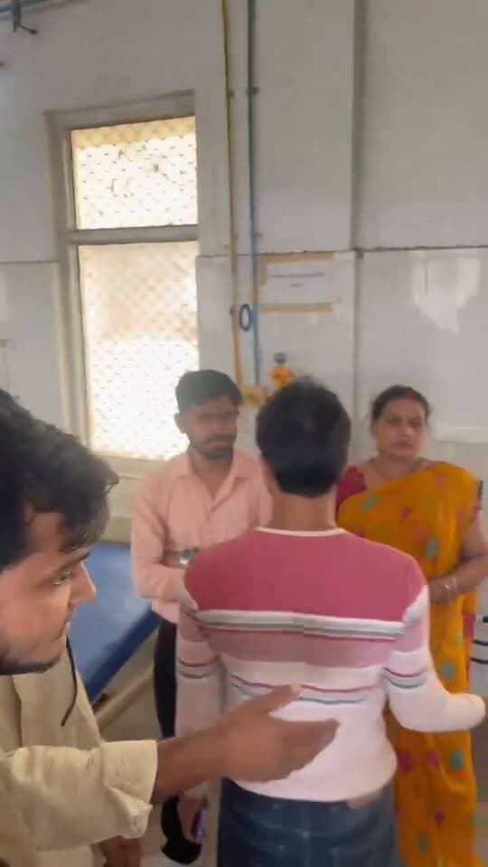 अम्बेडकर नगर मेडिकल कॉलेज में हंगामा: मरीज और तीमारदार के साथ मारपीट का आरोप, डॉक्टर और स्टाफ पर अभद्रता का दावा
अम्बेडकर नगर। राजकीय मेडिकल कॉलेज अम्बेडकर नगर एक बार फिर विवादों के घेरे में है। सोशल मीडिया पर तेजी से वायरल हो रहे एक वीडियो के आधार पर मरीज और उसके तीमारदारों ने मेडिकल कॉलेज के डॉक्टरों और अस्पताल स्टाफ पर गंभीर आरोप लगाए हैं। पीड़ित पक्ष का दावा है कि इलाज में लापरवाही का विरोध करने पर उनके साथ बदसलूकी और मारपीट की गई।
ड्रिप खत्म होने और खून बहने पर शुरू हुआ विवाद
वायरल वीडियो में देखा जा सकता है कि अस्पताल के बेड पर एक गंभीर रूप से घायल मरीज मौजूद है, जिसके सिर, हाथ और पैर पर पट्टियां बंधी हुई हैं। तीमारदार का आरोप है कि मरीज की ड्रिप (आईवी बोतल) पूरी तरह खत्म हो चुकी थी और रिफ्लेक्स के कारण कैनुला से खून बाहर निकलने लगा था। परिजनों का कहना है कि उन्होंने ड्यूटी पर मौजूद डॉक्टरों और स्टाफ को कई बार बुलाने की कोशिश की, लेकिन किसी ने ध्यान नहीं दिया।
"अपनी व्यवस्था खुद कर लो" कहने का आरोप
तीमारदार ने आरोप लगाया कि जब उन्होंने बार-बार डॉक्टरों से ड्रिप हटाने या बदलने का निवेदन किया, तो स्टाफ ने मदद करने के बजाय उनसे कह दिया कि "अपनी व्यवस्था खुद कर लीजिए"। इस पर जब तीमारदार ने घटना का वीडियो बनाना शुरू किया, तो वहां मौजूद स्टाफ और डॉक्टरों से बहस हो गई।
वीडियो बनाने पर हाथापाई और मारपीट
वीडियो में देखा जा सकता है कि मोबाइल से रिकॉर्डिंग शुरू होते ही अस्पताल का माहौल गरमा गया। तीमारदारों का आरोप है कि वीडियो बनता देख अस्पताल स्टाफ आपा खो बैठा और उनके साथ हाथापाई करते हुए मारपीट की गई।
प्रशासन से कार्रवाई की मांग
घटना का वीडियो सोशल मीडिया पर वायरल होने के बाद स्थानीय लोगों में भारी आक्रोश है। पीड़ित परिजनों ने उच्च अधिकारियों और पुलिस प्रशासन से मेडिकल कॉलेज के दोषी डॉक्टरों व कर्मचारियों के खिलाफ सख्त कानूनी एवं प्रशासनिक कार्रवाई की मांग की है।