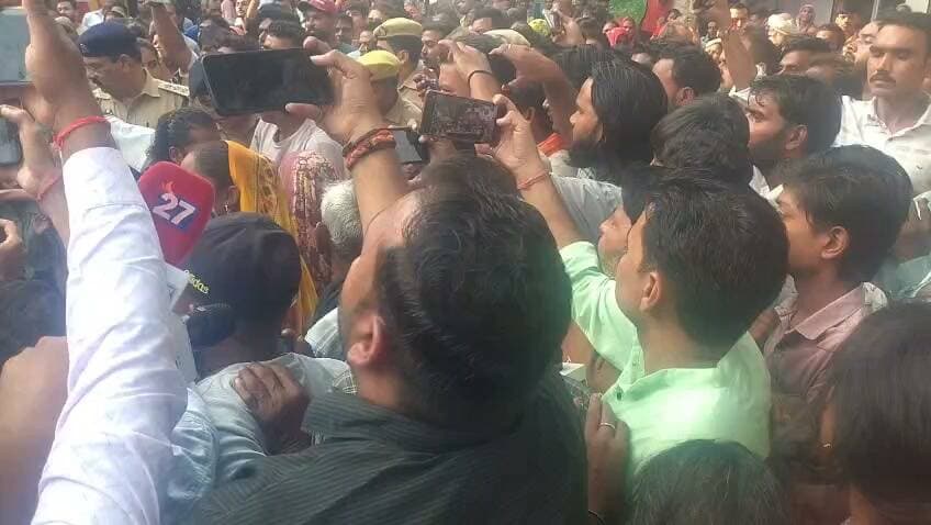 हमीरपुर में फल विक्रेता की मौत का मामला नया मोड़ ले चुका है। परिजन उन्हें फर्श पर गिरने से घायल बताकर अस्पताल लाए थे, लेकिन पोस्टमार्टम में गोली लगने की पुष्टि हुई। कानपुर में इलाज के दौरान मौत के बाद परिजनों ने कालपी चौराहे पर शव रखकर जाम लगा दिया। उनकी मांग है कि दोषियों पर कार्रवाई हो और परिवार के एक सदस्य को नौकरी दी जाए। मौके पर भारी पुलिस बल तैनात है और अधिकारी परिजनों को समझाने में जुटे हैं