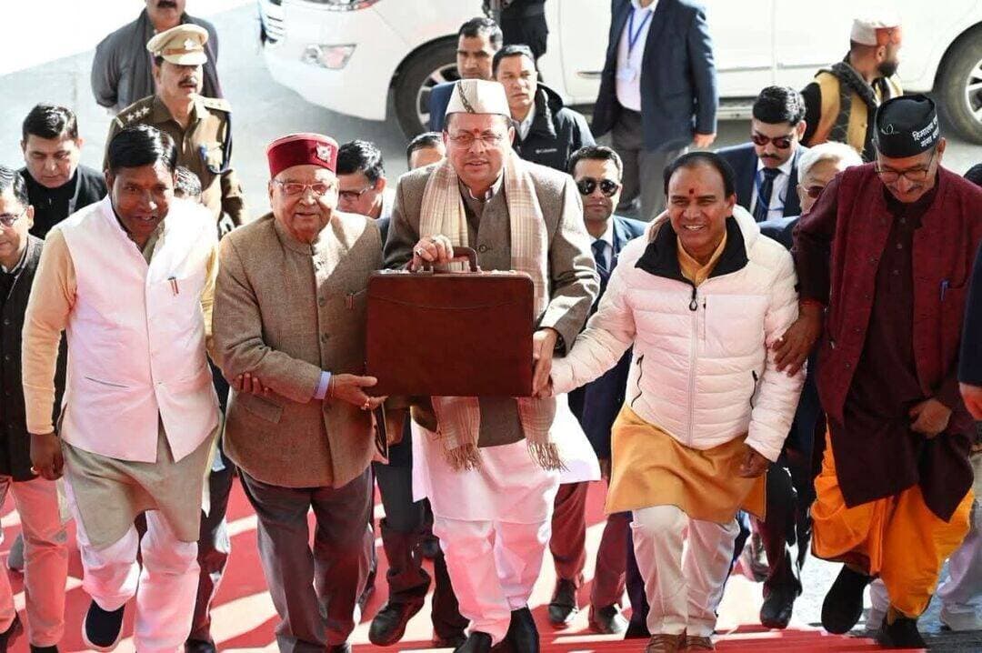 सूटकेस में बजट लेकर विधानसभा पहुंचे CM धामी! भगत जी और धन सिंह जी ने दिया सहारा।