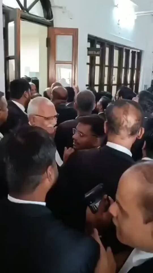 इलाहाबाद हाईकोर्ट में जस्टिस अजय भनोट की अदालत में वकीलों का हंगामा, कोर्ट रूम नंबर 49 में तोड़फोड़
प्रयागराज, इलाहाबाद हाईकोर्ट परिसर में आज सुबह जस्टिस अजय भनोट की कोर्ट रूम नंबर 49 में वकीलों ने भारी हंगामा किया और तोड़फोड़ की। घटना इतनी गंभीर हो गई कि सुरक्षाबलों को जस्टिस भनोट को पिछले दरवाजे से सुरक्षित बाहर निकालना पड़ा।मामले की जड़ 27 अक्टूबर को हुई घटना में छिपी है। हाईकोर्ट बार एसोसिएशन के अनुसार, जस्टिस भनोट ने कोर्ट रूम में पुलिस अधिकारियों व अन्य वरिष्ठ अधिकारियों के लिए अगली पंक्ति में अलग कुर्सी रखने की प्रथा शुरू की है।एक मामले में सुनवाई के दौरान औरैया के पुलिस अधीक्षक अभिषेक भारती अतिरिक्त सरकारी अधिवक्ता के पीछे बैठे थे। एक अधिवक्ता ने सम्मानपूर्वक उनसे पीछे बैठने को कहा कि “यह आपकी सीट नहीं है।” इस पर अधिवक्ता को डांटा गया और जज से शिकायत करने की बात कही गयी। जस्टिस भनोट के आने पर शिकायत की गई, जिसके बाद कथित तौ�