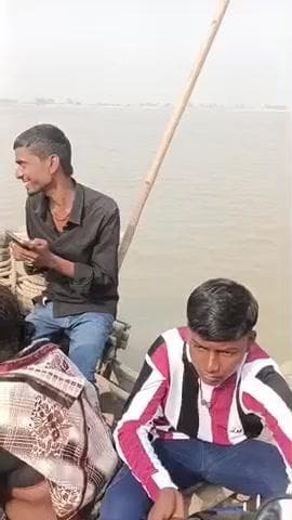 गंगा नदी से पार कर रहे यात्री नाव में